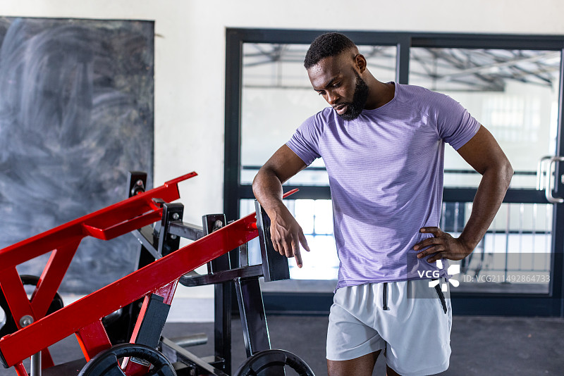 非裔美国青年男运动员站在健身房器材旁沉思图片素材