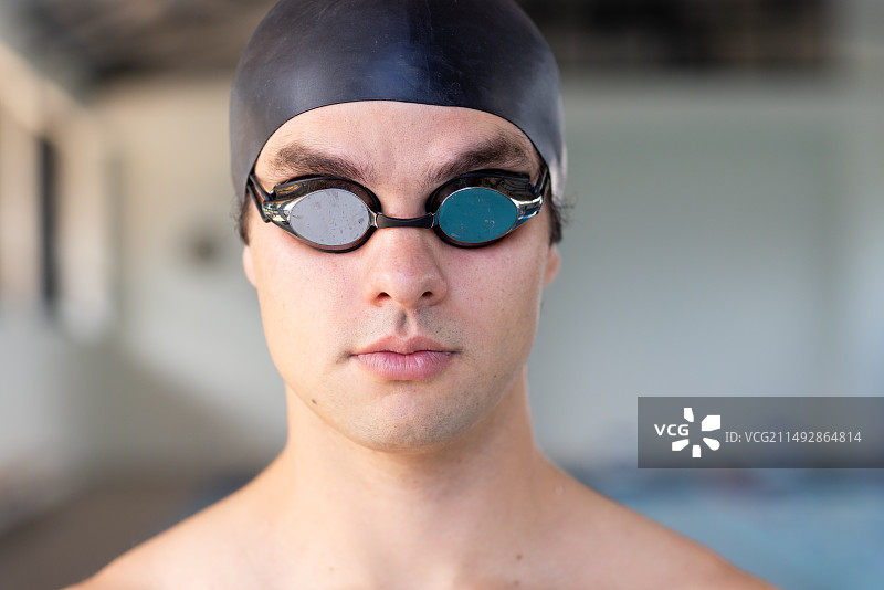 戴着护目镜和泳帽，准备在室内游泳的年轻白人男性游泳者图片素材