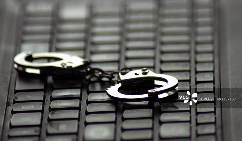 笔记本电脑键盘上的手铐特写镜头图片素材