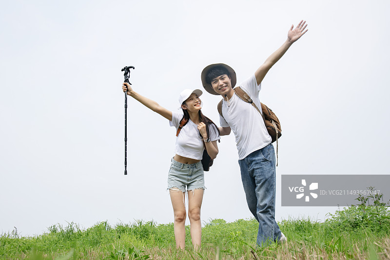 户外徒步站在山顶的年轻情侣图片素材