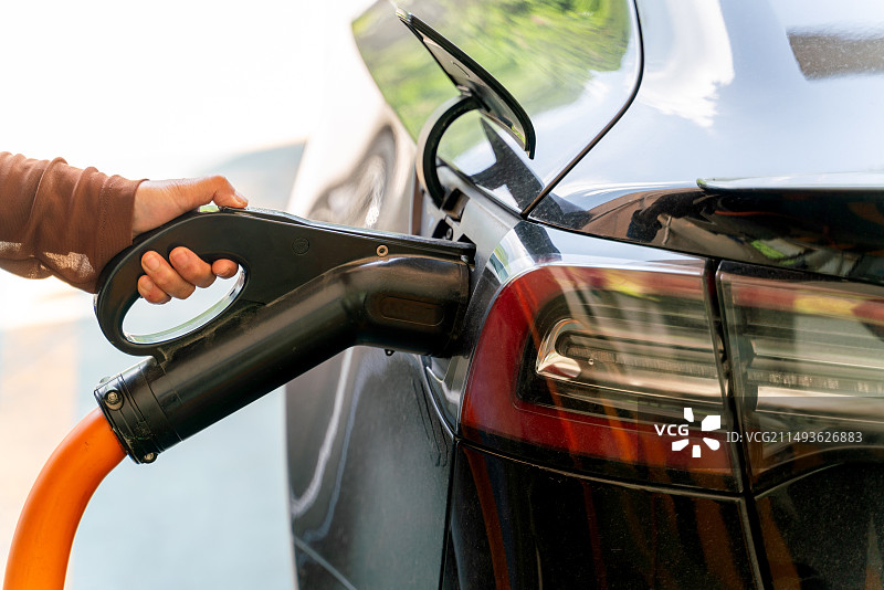 手持充电枪给电动汽车充电图片素材