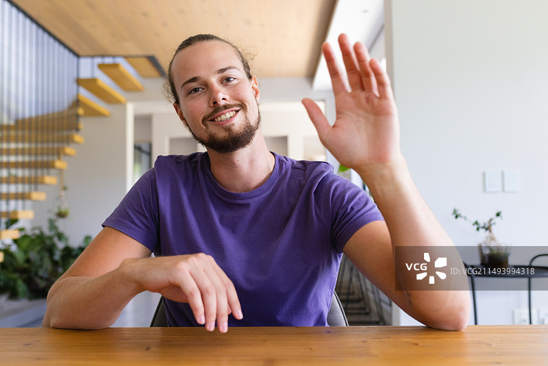 在家中视频通话中挥手问好的年轻白人男子图片素材