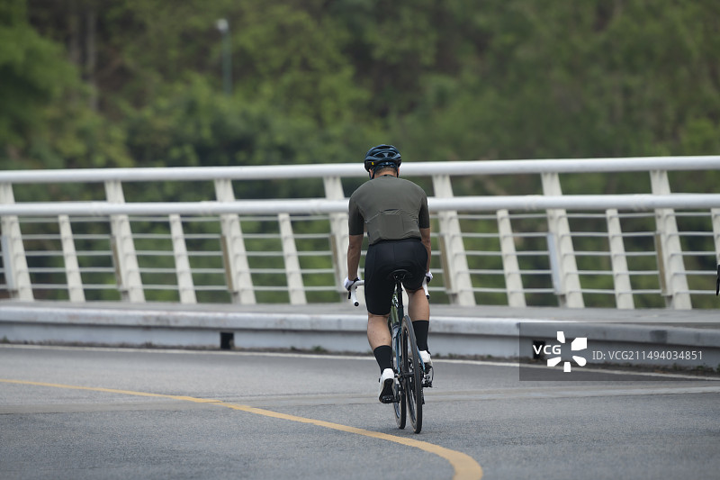 年轻人在柏油路弯道上骑行图片素材