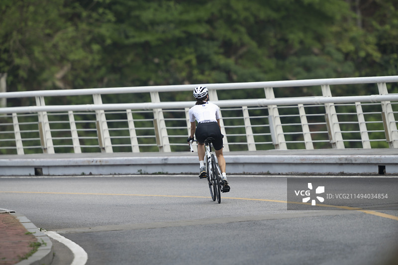 年轻人在柏油路弯道上骑行图片素材