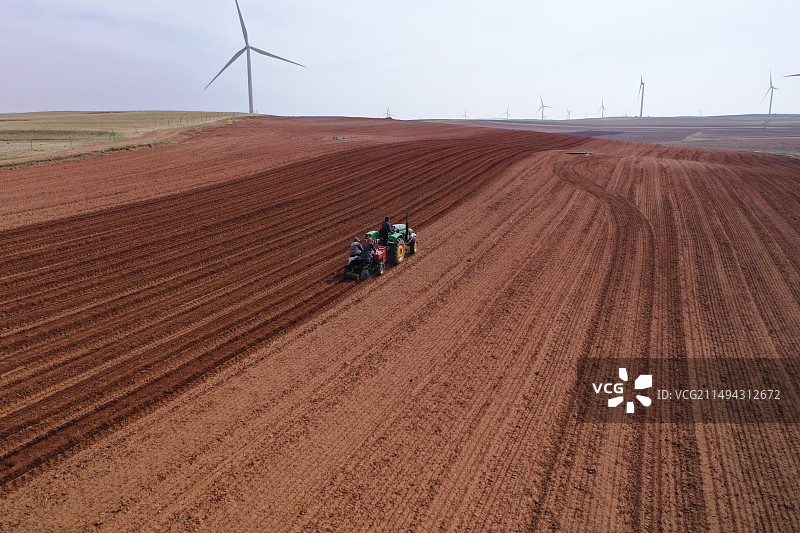 航拍内蒙古呼和浩特武川县农业农民开着四轮拖拉机春耕耕地在红土地种土豆图片素材