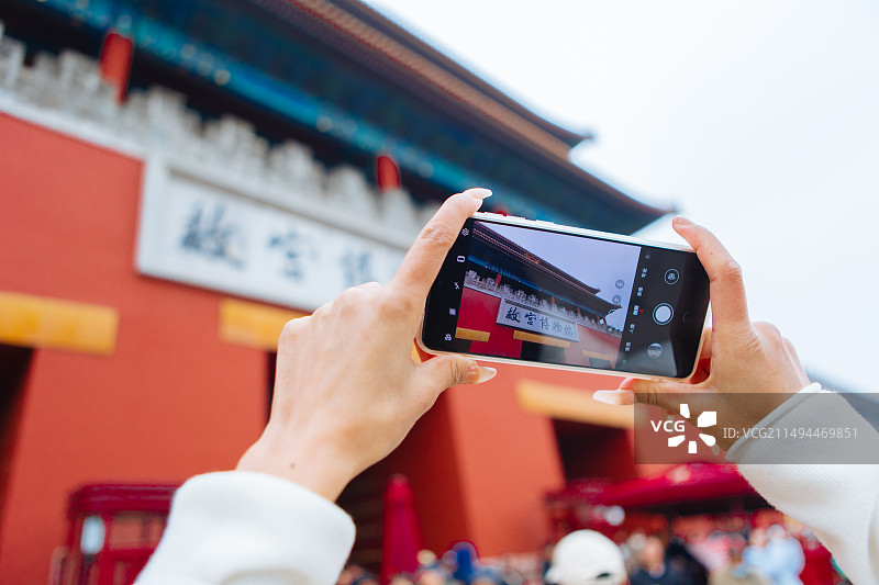 游客拿着手机拍照打卡故宫博物馆图片素材