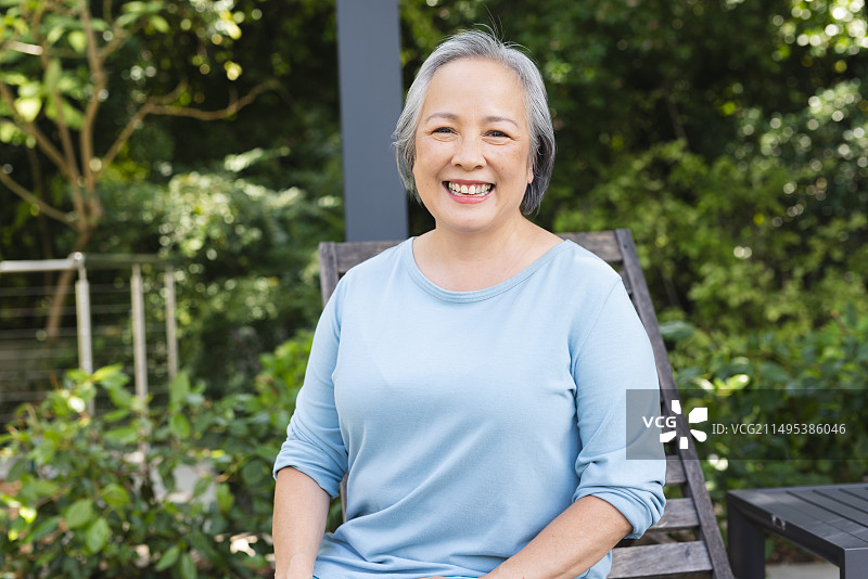 亚洲老年女性坐在户外，对着镜头微笑图片素材