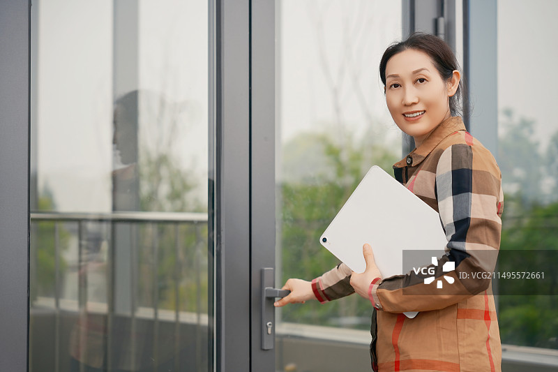 职业女性手持平板电脑走进办公楼图片素材