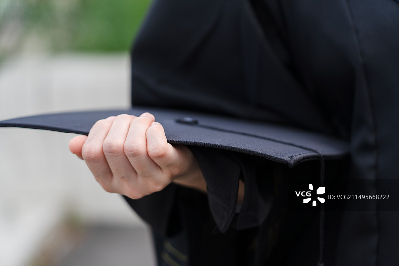 毕业生手拿学士帽图片素材