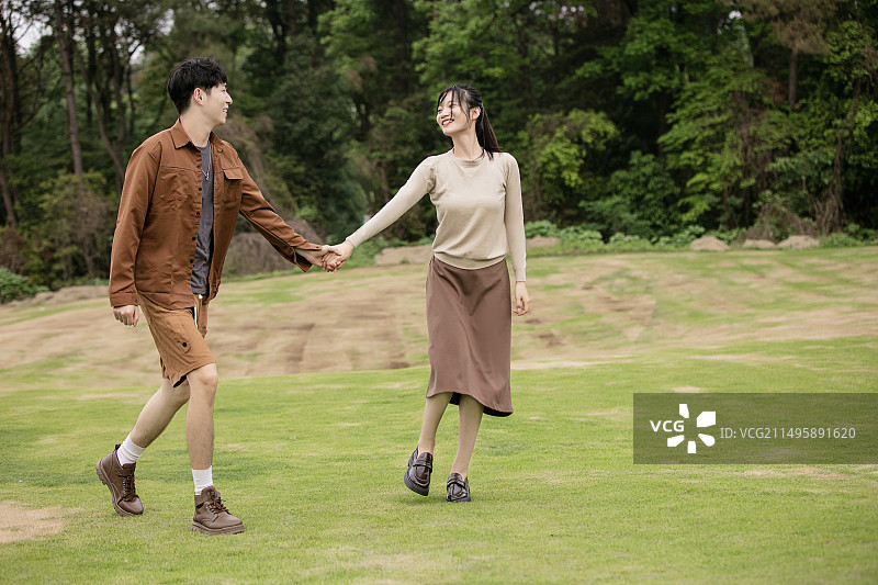 年轻的情侣在草坪上追逐嬉戏图片素材