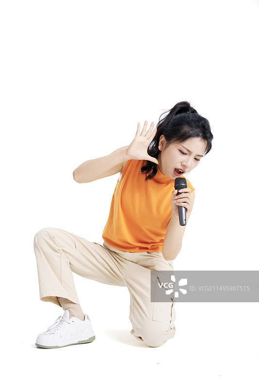坐在地上手拿麦克风唱歌的年轻中国女大学生图片素材