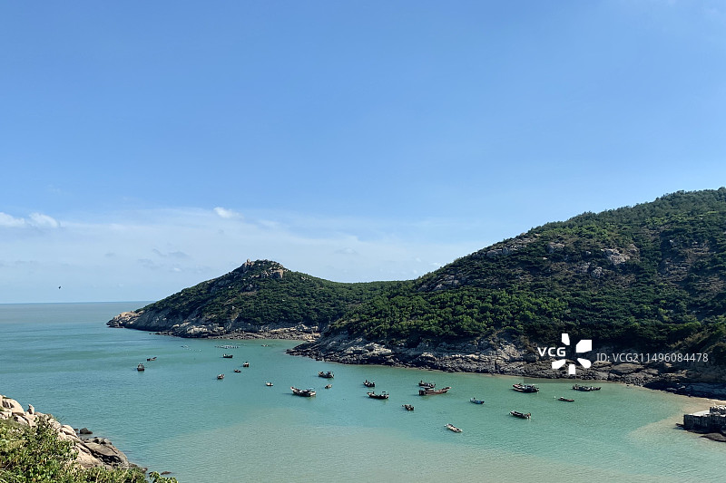 温州南麂岛，蓝天白云下海湾里的渔船与远处的高山图片素材