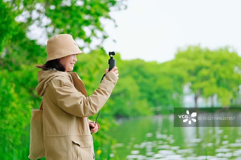 女人在镜头上捕捉宁静湖的瞬间图片素材