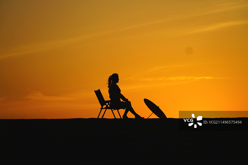 夕阳下坐在椅子上的人的剪影图片素材