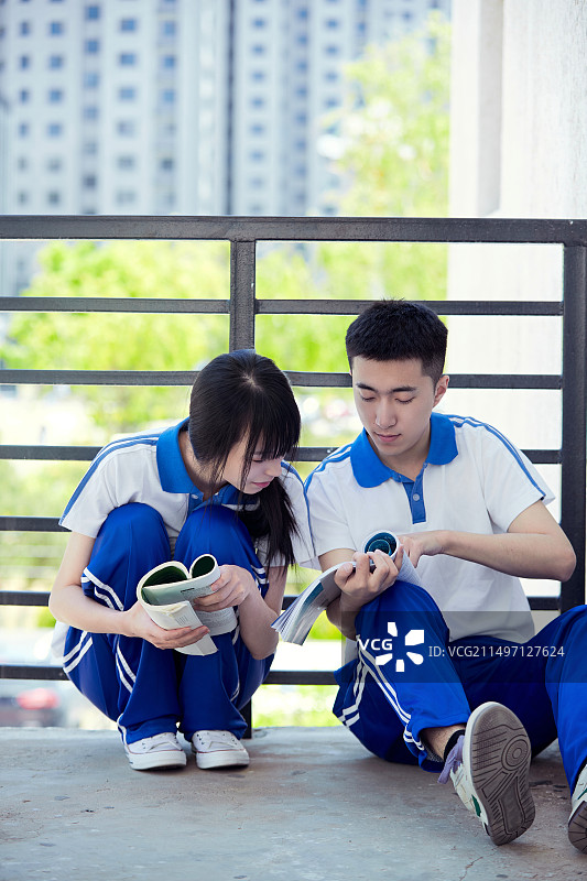 在学校教学楼阳台复习看书的高中生图片素材