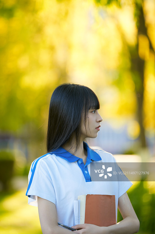 校园里抱着书的高中女生图片素材