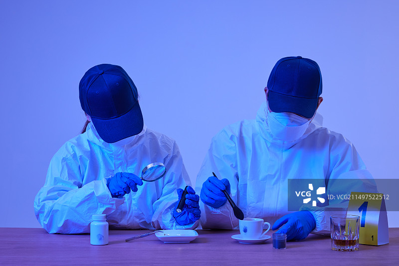 犯罪现场调查科男女研究员在犯罪和事故现场用蓝光收集指纹，并用放大镜检查证据图片素材