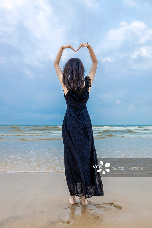 穿黑色长裙的内女在海边看海图片素材