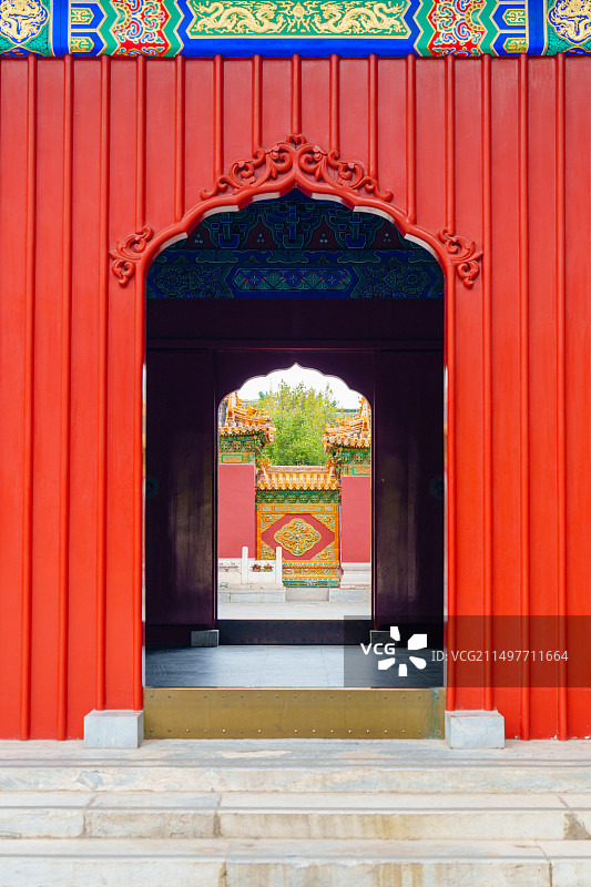 透过北海公园西天梵境庙宇门洞看红墙上用琉璃砖砌的中国龙图片素材
