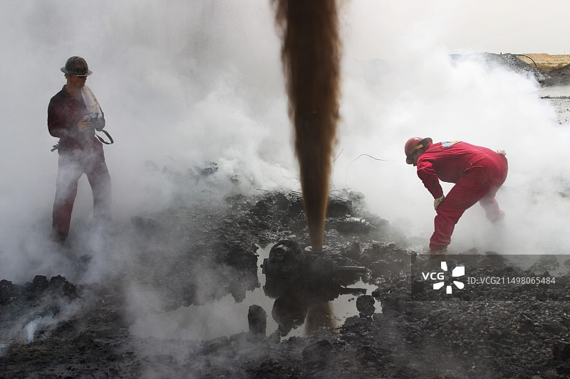 消防员评估喷涌的油井图片素材