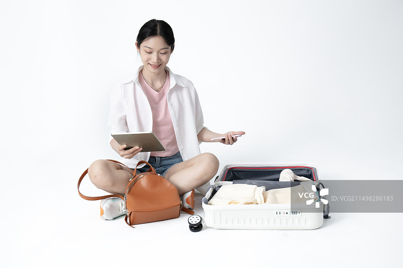 坐在地面整理旅行箱听着音乐的年轻女学生图片素材