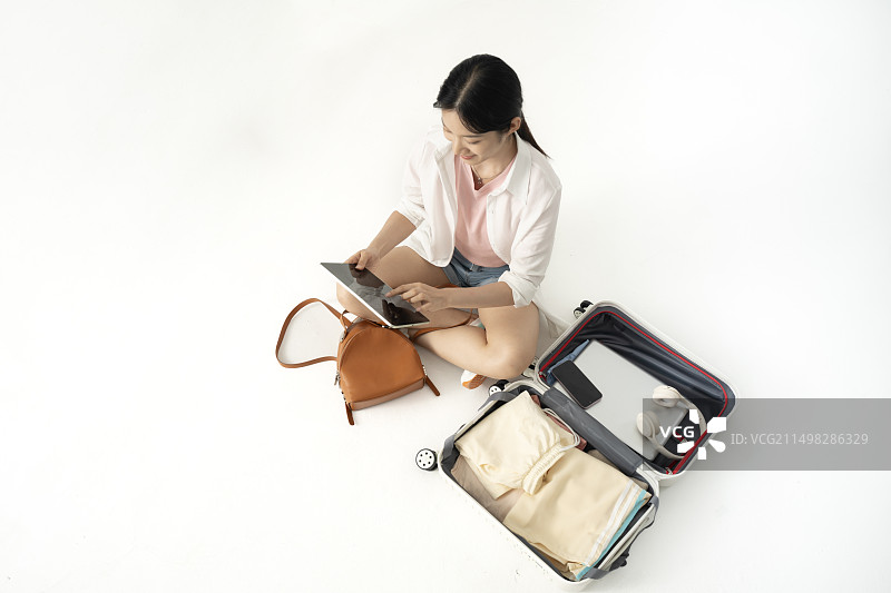 高角度下年轻女学生与打开的旅行箱图片素材