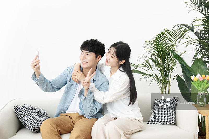 坐在沙发上一起使用手机的年轻情侣图片素材
