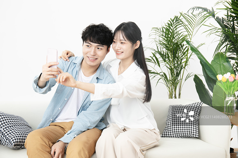 坐在沙发上一起使用手机的年轻情侣图片素材
