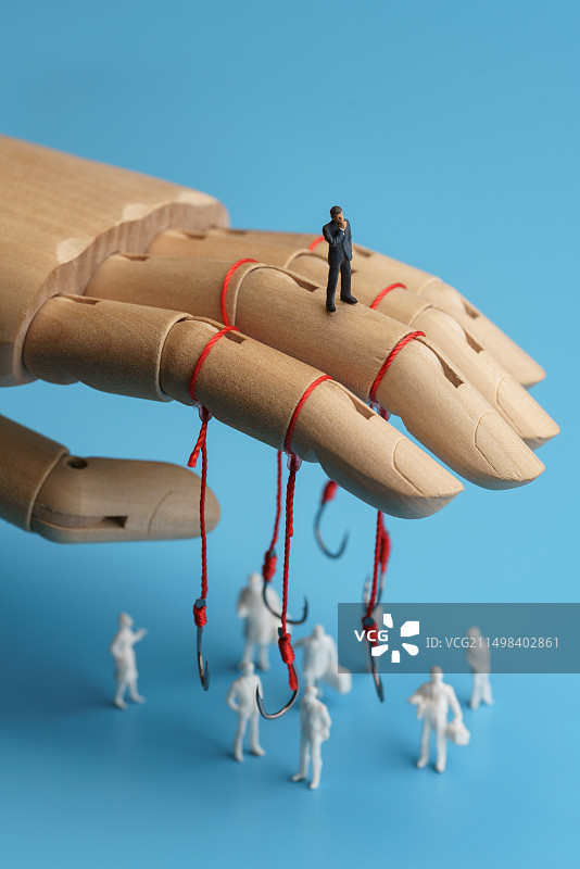 挂满鱼钩的木偶手下站着的人群微缩创意图图片素材