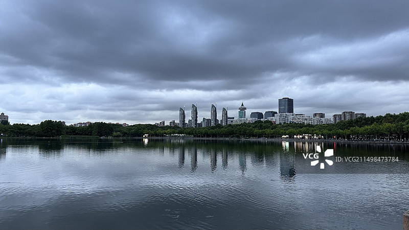上海世纪公园，阴云下的湖面和远处的城市天际线，乌云密布图片素材