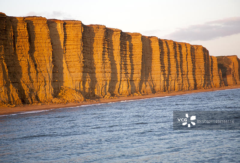 英国多塞特郡西湾东崖砂岩悬崖上的金色午后光线图片素材