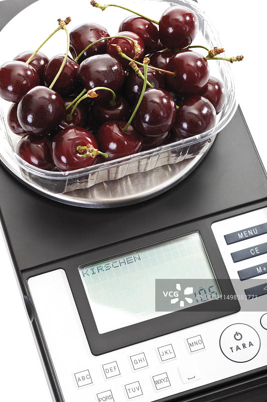 weighing scale上塑料盒中的酸樱桃图片素材
