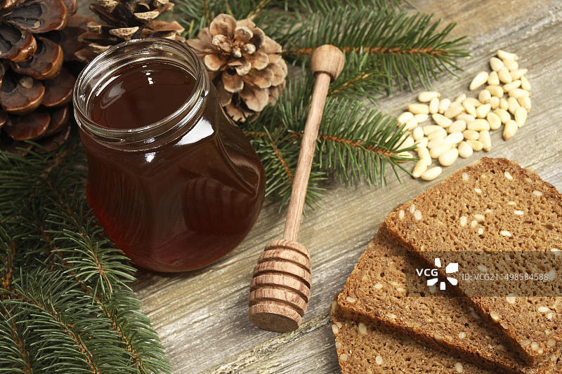 森林蜂蜜、全麦面包、冷杉枝和冷杉锥图片素材