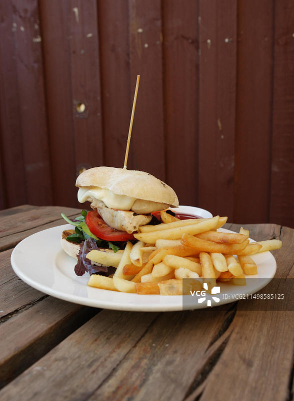 乡村木桌上的汉堡、炸薯条和番茄酱快餐图片素材