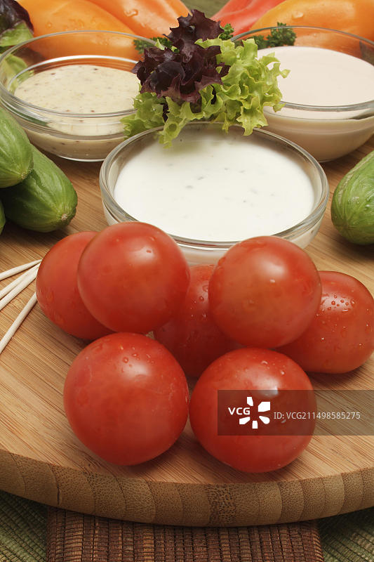 木制砧板上的迷你甜椒、小番茄、迷你小黄瓜、生菜、酸奶蘸酱、美式蘸酱和蜂蜜芥末蘸酱图片素材