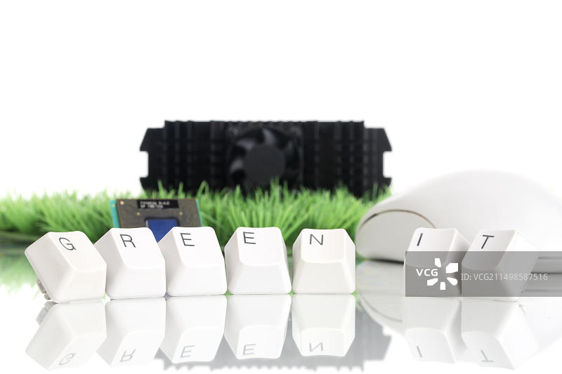 处理器芯片、散热风扇和鼠标在人造草皮上，键盘字母组成“绿色IT”图片素材