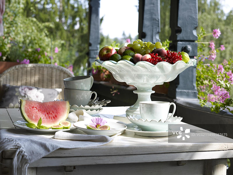 夏日阳台露台上带有精美瓷器水果碗的咖啡桌静物图片素材