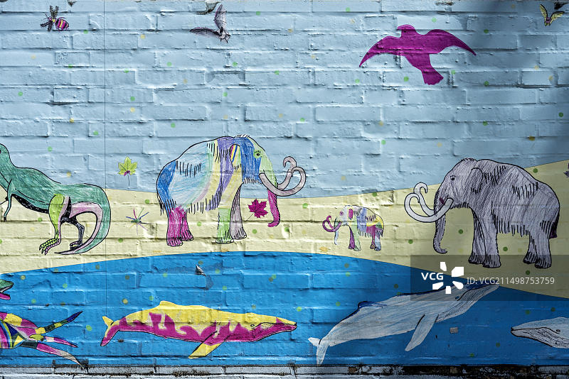 史前时代的水陆空动物：鲸鱼、猛犸象、翼龙，色彩鲜艳的儿童画，位于德国黑森州吉森市李比希大学赫尔曼·霍夫曼学院墙上图片素材