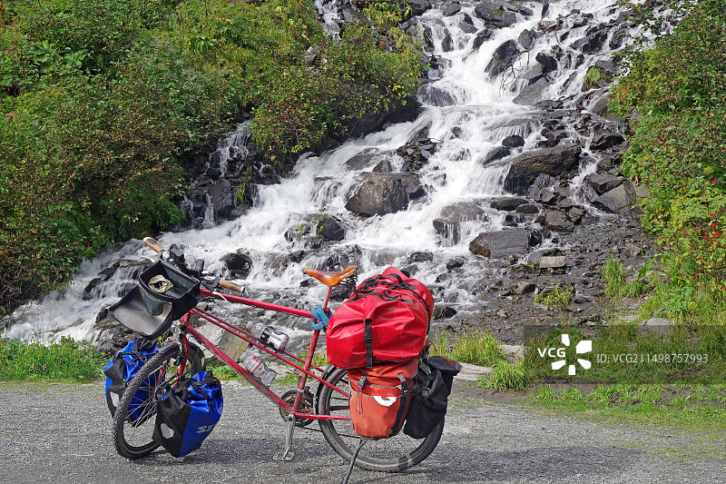 美国阿拉斯加州瓦尔迪兹理查森公路汤普森山口楚加奇山脉瀑布前的带行李自行车图片素材