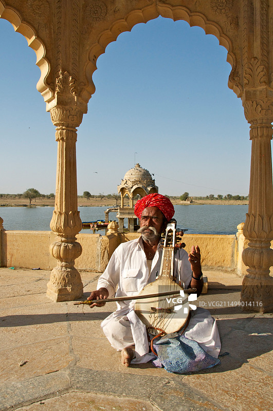 音乐家在印度拉贾斯坦邦斋沙默尔的加迪萨加尔湖演奏卡曼奇琴图片素材
