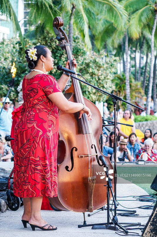 夏威夷火奴鲁鲁威基基海滩库希欧海滩公园凯悦酒店的呼啦舞表演者、自由歌手、音乐家、贝斯手和穿着muumuu的女人在美国用麦克风表演图片素材