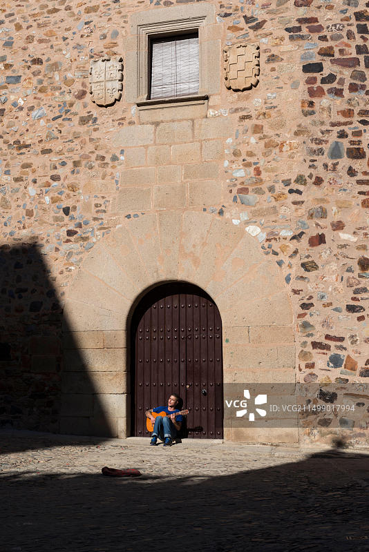 街头音乐家在西班牙卡塞雷斯公爵府门口弹吉他图片素材