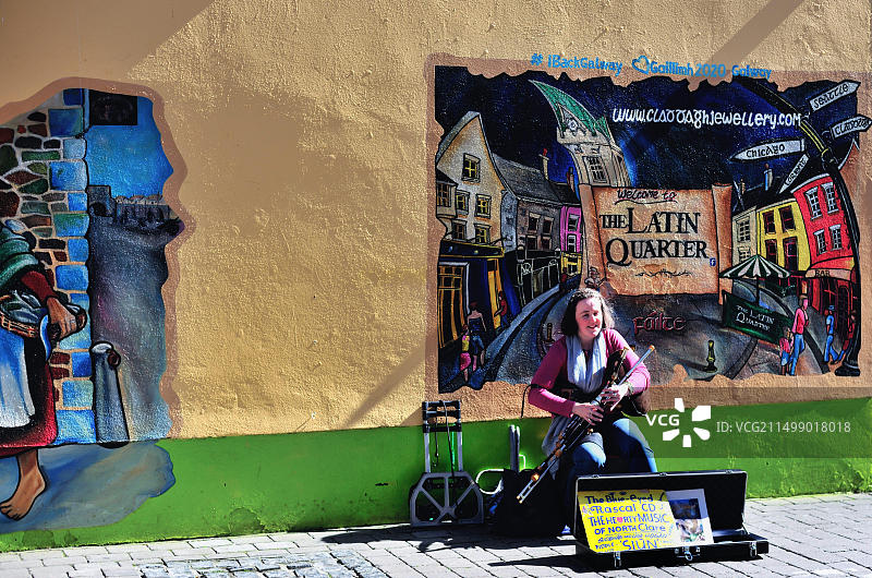 在爱尔兰戈尔韦郡拉丁区一家商店的壁画面前演奏传统爱尔兰音乐的街头音乐家图片素材
