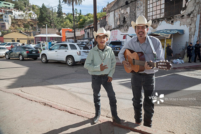 墨西哥索诺拉州诺加莱斯：街头音乐家为排队一小时等待过境进入美国的行人演奏图片素材