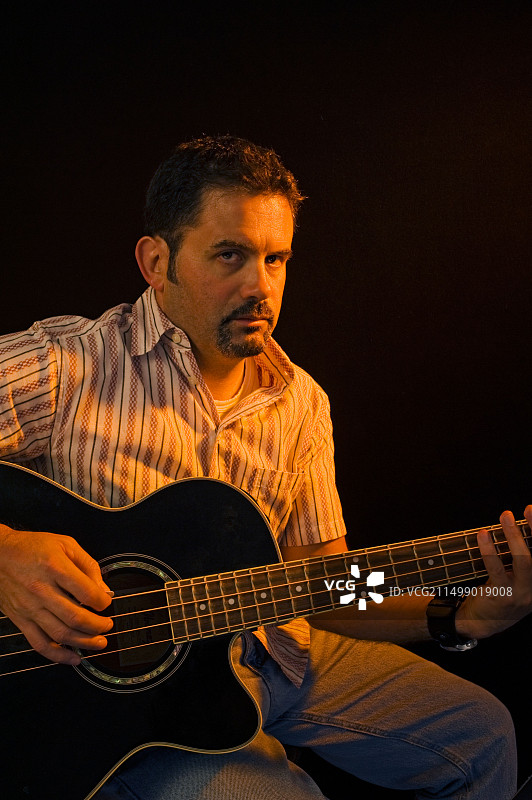 聚光灯下弹贝斯吉他的音乐人图片素材