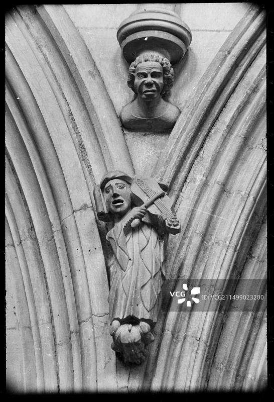 中殿雕刻精美的风帽模具止动器的详细视图，展示了一个演奏弓弦乐器的形象，上方有一个人物的躯干。图片素材