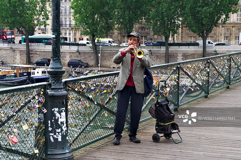 街头音乐家在巴黎塞纳河的桥上吹小号图片素材