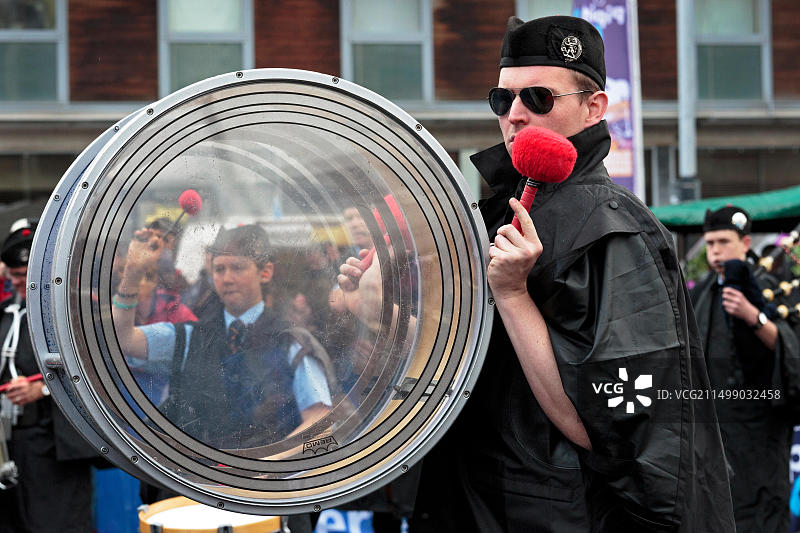 鼓号长演奏他的透明低音鼓，远处是一个年轻女孩演奏边鼓的图像，格拉斯哥图片素材