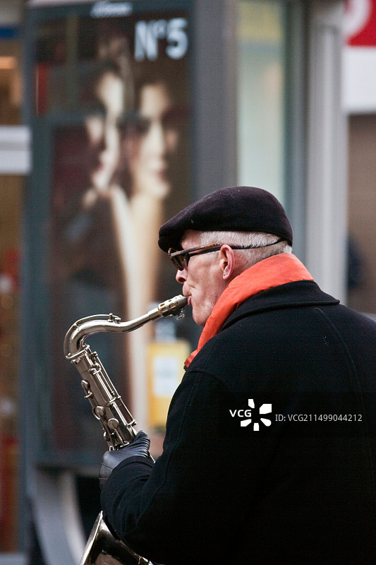 英国诺丁汉市中心，在广告牌前演奏萨克斯管的养老金领取者图片素材