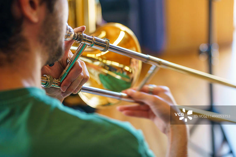 从背后看，男人演奏长号的特写图片素材